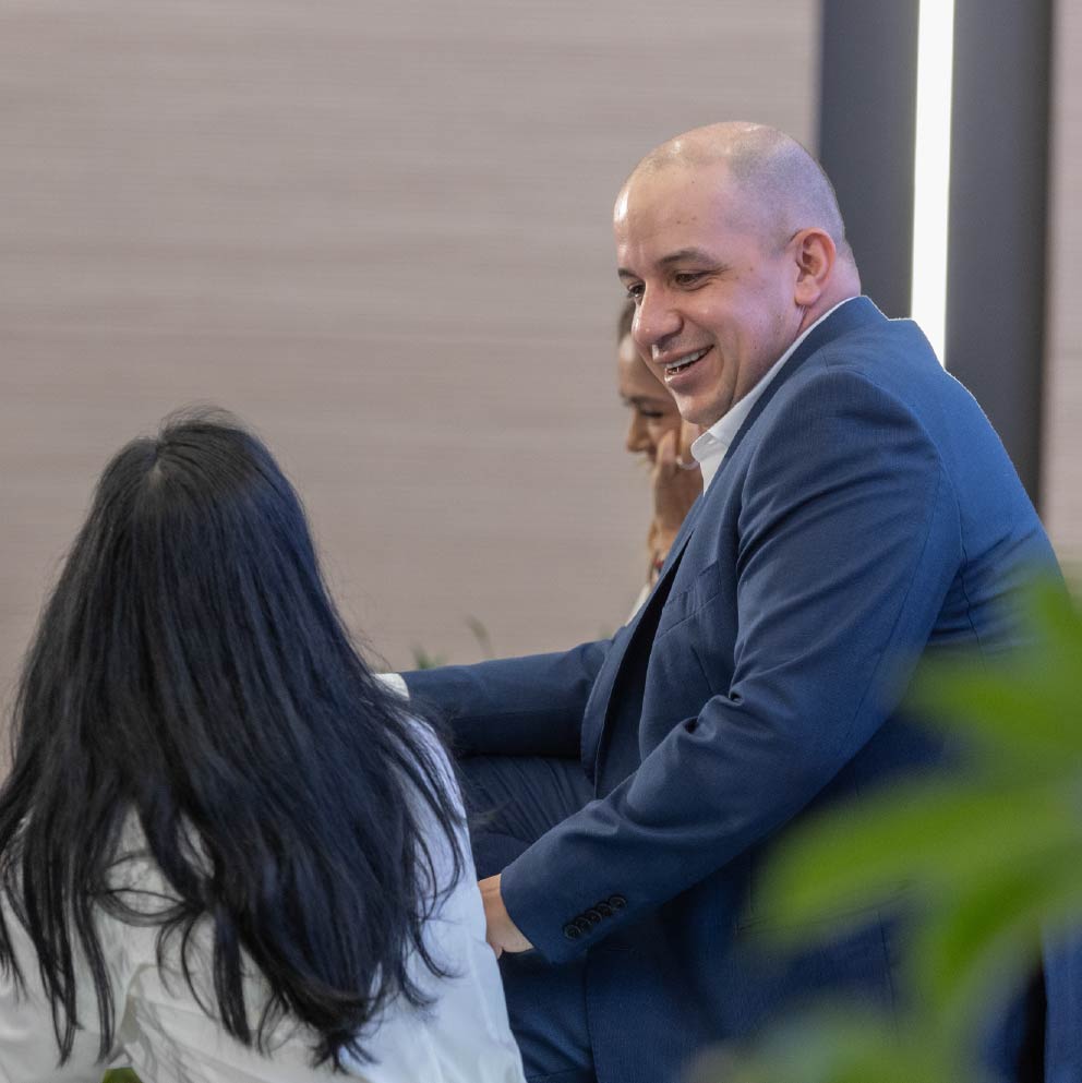 Foto de Jorge Carrillo sonriendo, mientras habla con alguien más